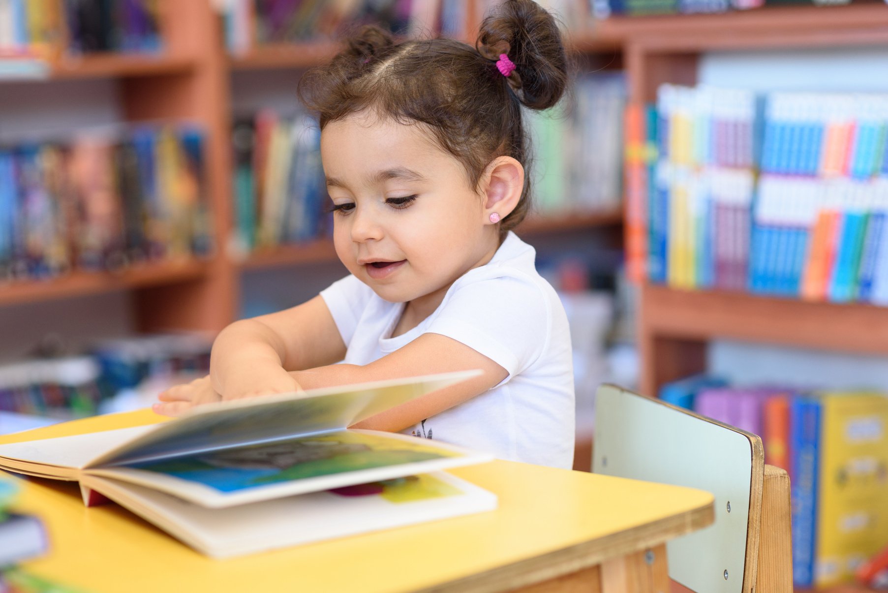 Happy child little girl reading a book.